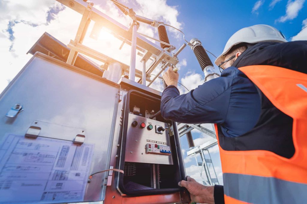 A worker in orange and safety vest is seen working on a power plant.