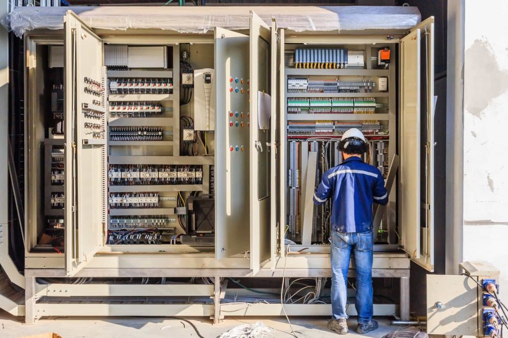 A man working on a large electrical panel, ensuring the smooth functioning of the system.