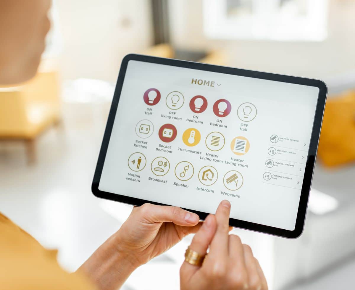 Woman holding tablet displaying home automation icons.