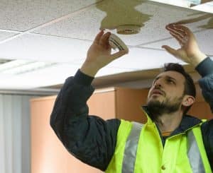 A man in a safety vest Installing a Fire Alarm System